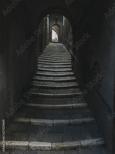 Low angle urban view of tunnel with streets going up to the light in old medieval town from Italy
