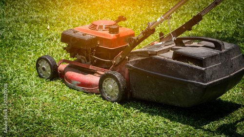 The rear view of the workers is using a lawn mower on the ground. photo