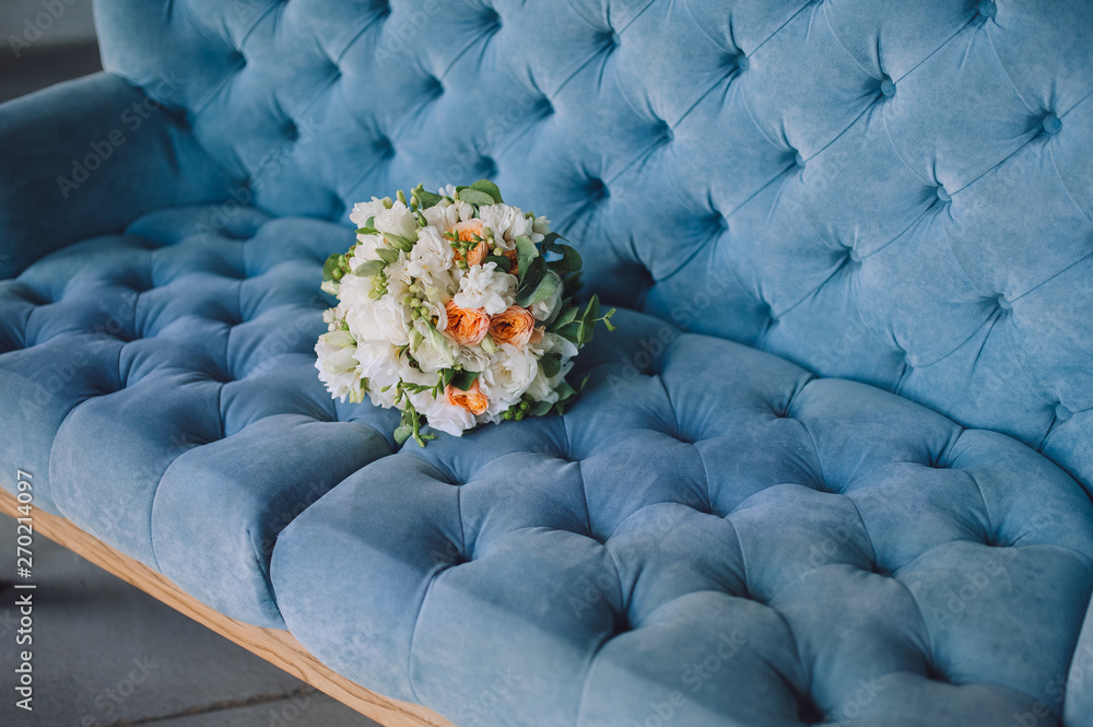Obraz premium Multi-colored wedding bouquet with wildflowers and roses lies on the background of a blue sofa. Wedding photography, copy space, poster.