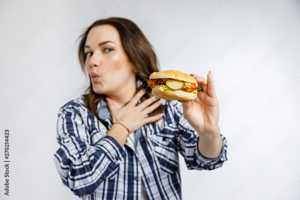Young beautiful girl holding a Burger on a white background. Fast food, junk food, snack on the go. Young beautiful girl holding a Burger on a white background. Fast food, junk food, snack on the go.