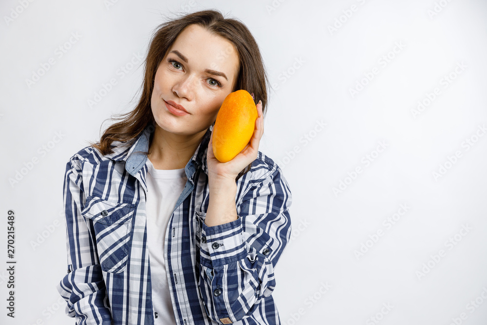Young beautiful girl in plaid shirt holding mango on white background. Healthy food - vegetables, fruits and berries. Young beautiful girl in plaid shirt holding mango on white background. Healthy food - vegetables, fruits and berries.