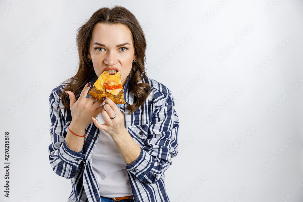 A young beautiful girl takes a piece in a plaid shirt on a white background. A young beautiful girl takes a piece in a plaid shirt on a white background.