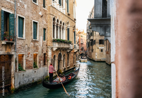 Venetian gondolier punts gondola through narrow canal waters of Venice Italy