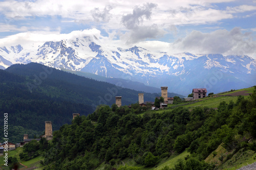 View of the towers of the village of Mestia against the background of snow-capped peaks and cloudy skies in the Upper Svaneti region, Georgia