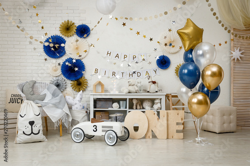 Birthday decorations with gifts, toys, garlands and figure for little baby party on a white bricks background. 