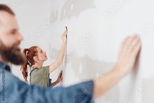 Young woman sanding an unpainted clad wall photo