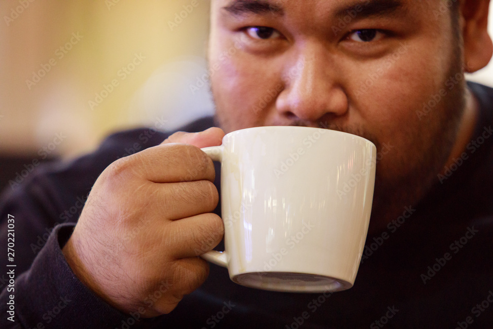 Hands of the male and the white coffee cup in the cafe,Men are drinking coffee in the morning Hands of the male and the white coffee cup in the cafe,Men are drinking coffee in the morning