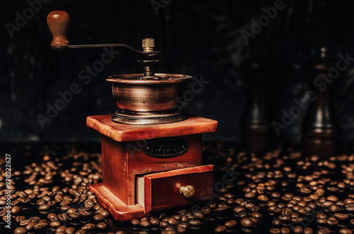 Old wooden coffee grinder and coffee beans on concrete background.