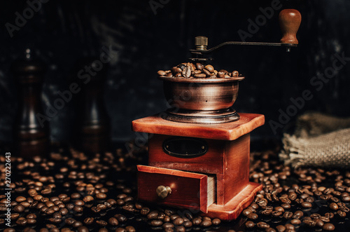 Old wooden coffee grinder and coffee beans on concrete background.