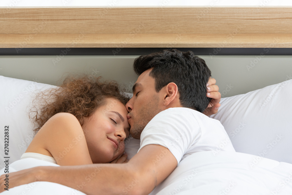 Happy couples relaxing in the white bedroom Of the apartment With various emotions With snacks, coffee, fruit in the morning Happy couples relaxing in the white bedroom Of the apartment With various emotions With snacks, coffee, fruit in the morning