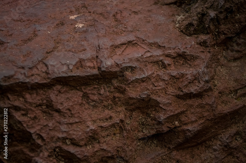 Background or texture from a red stone with cracks and the broken-away parties with an impregnation a moss. Natural material.