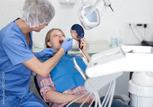 Dentist male in uniform is examinating of female in dental clinic