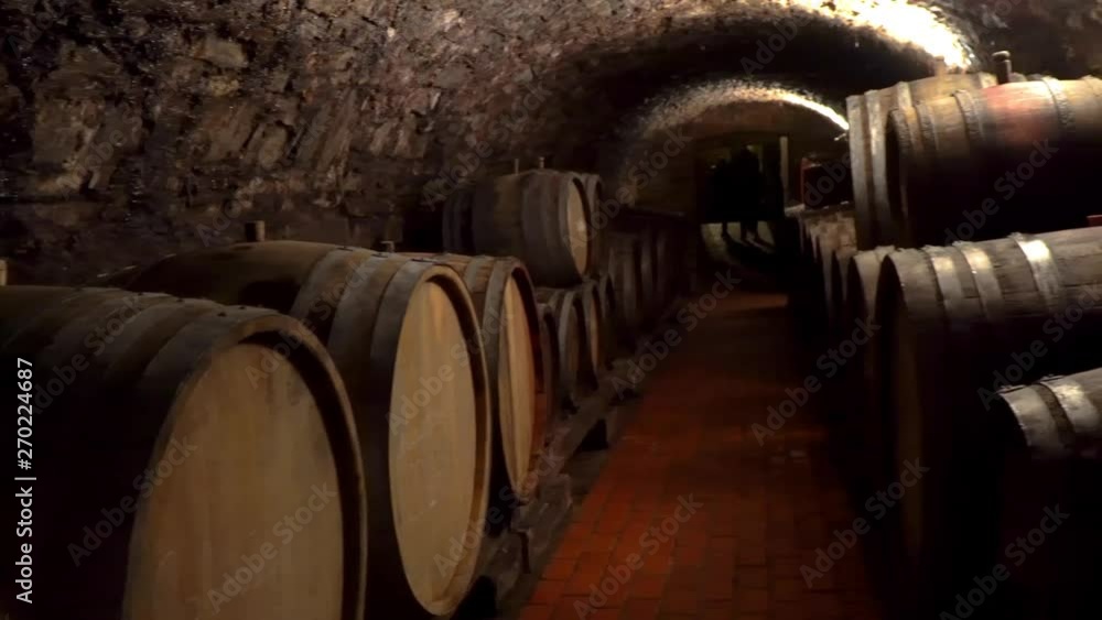 Wine is stored in wooden barrels in an old wine cellar. A lot of wine barrels stacked in a cellar. Wine is stored in wooden barrels in an old wine cellar. A lot of wine barrels stacked in a cellar.