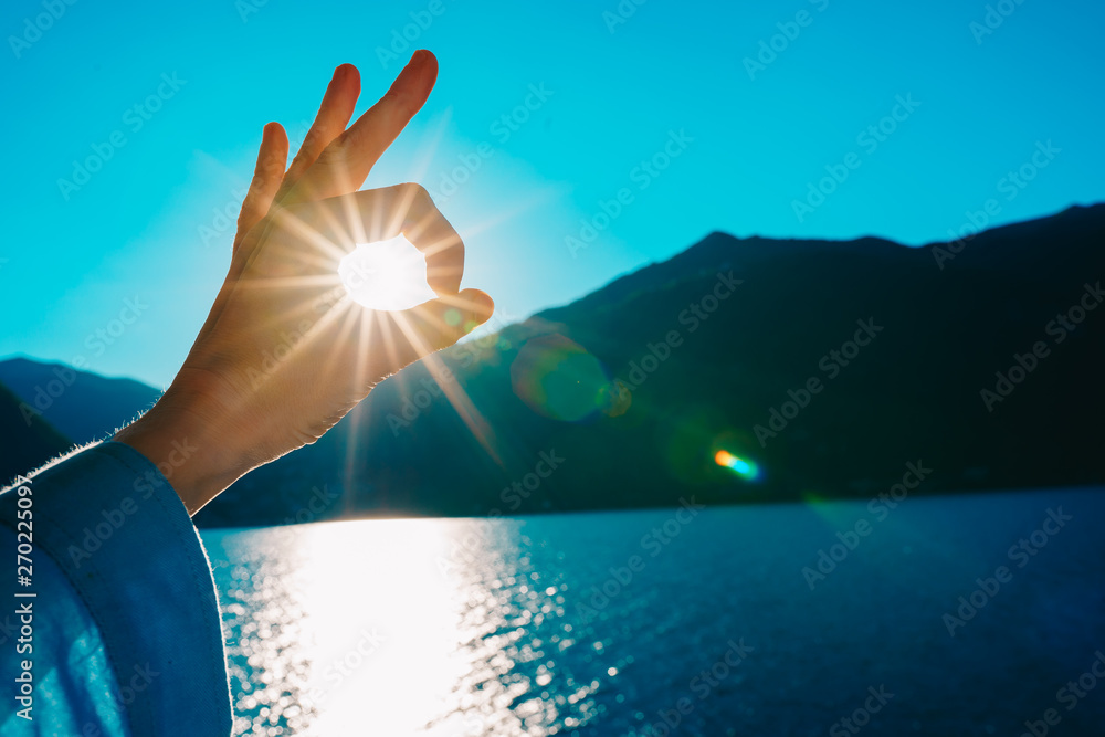 Hand OK sign on the sunlight. The sun shines through the hand.	