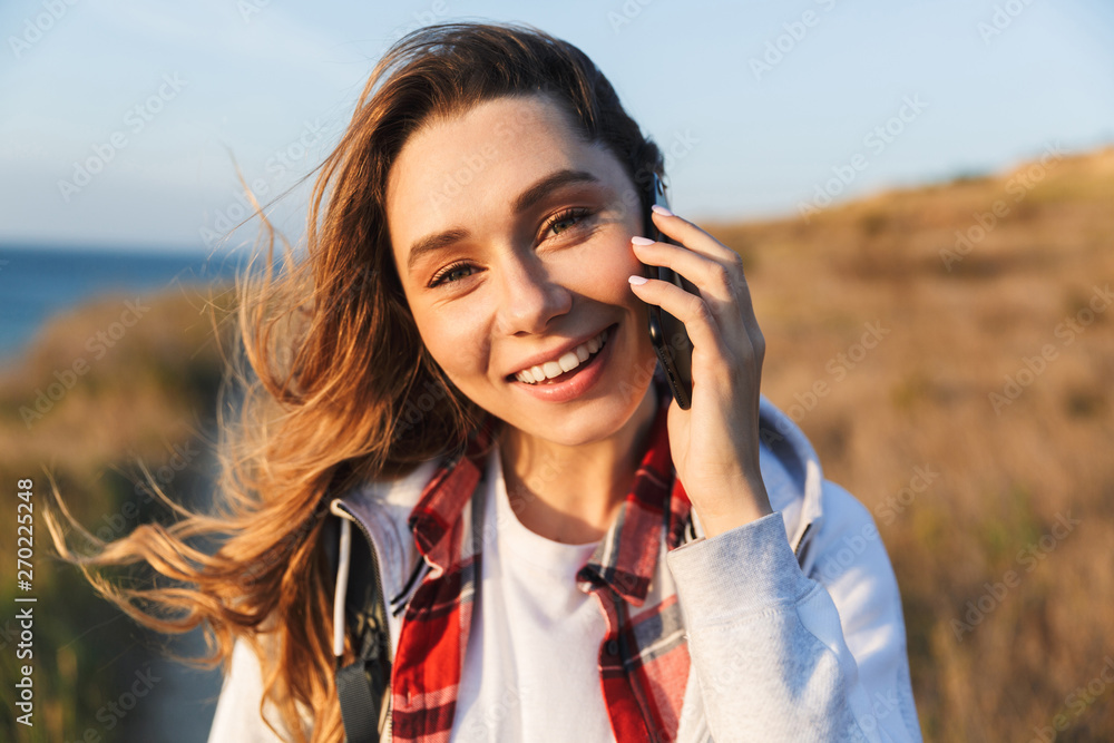 Happy young woman outside in free alternative vacation camping talking by mobile phone.