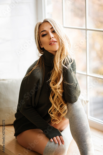 Gentle and attractive blonde in a sweater at home