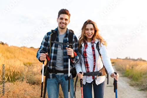 Happy young loving couple outside with backpack in free alternative vacation camping.