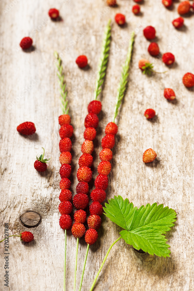 Fresh wild strawberries in three blade of grass on a old wooden surface. Natural organic healthy food concept. Fresh wild strawberries in three blade of grass on a old wooden surface. Natural organic healthy food concept.