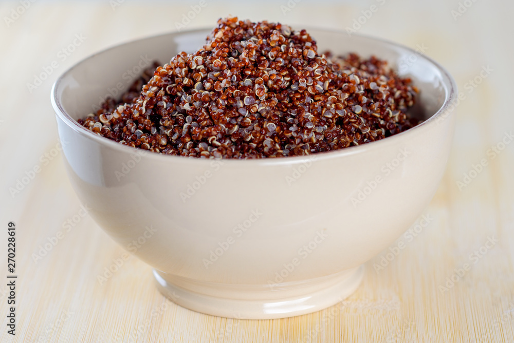 Red quinoa in a bowl on a wooden background. Red quinoa in a bowl on a wooden background.