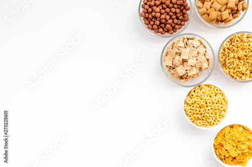 Various corn cereals in bowls on white background top view copyspace