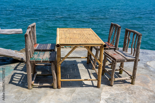 Bamboo table and wooden chairs in empty cafe next to sea water in tropical beach . Island Koh Phangan  Thailand