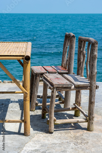 Bamboo table and wooden chairs in empty cafe next to sea water in tropical beach . Island Koh Phangan  Thailand