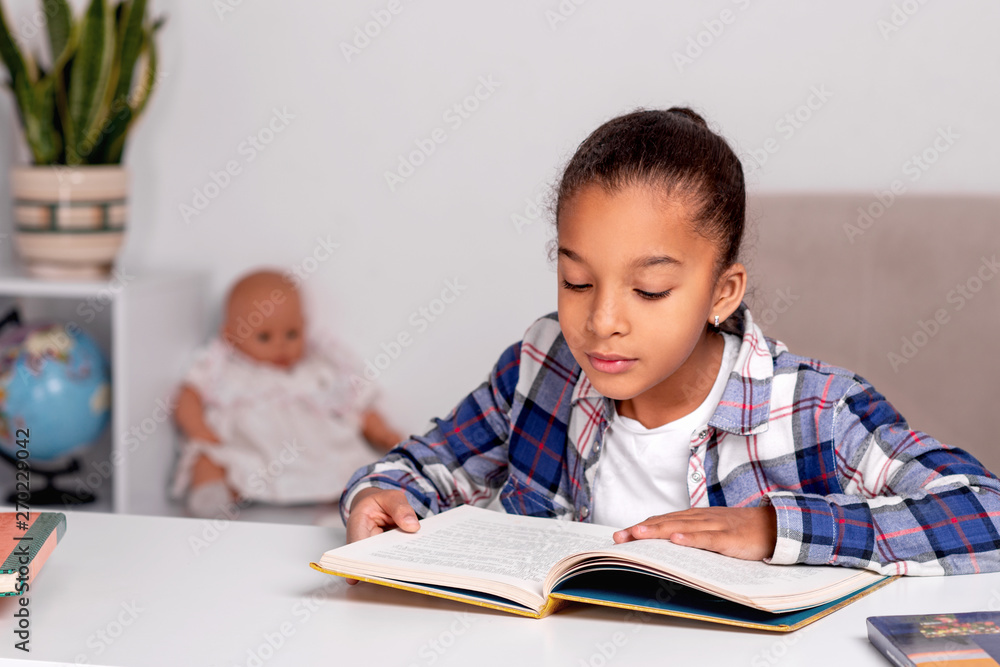 The schoolgirl sits at the table at home and does his homework. The schoolgirl sits at the table at home and does his homework.