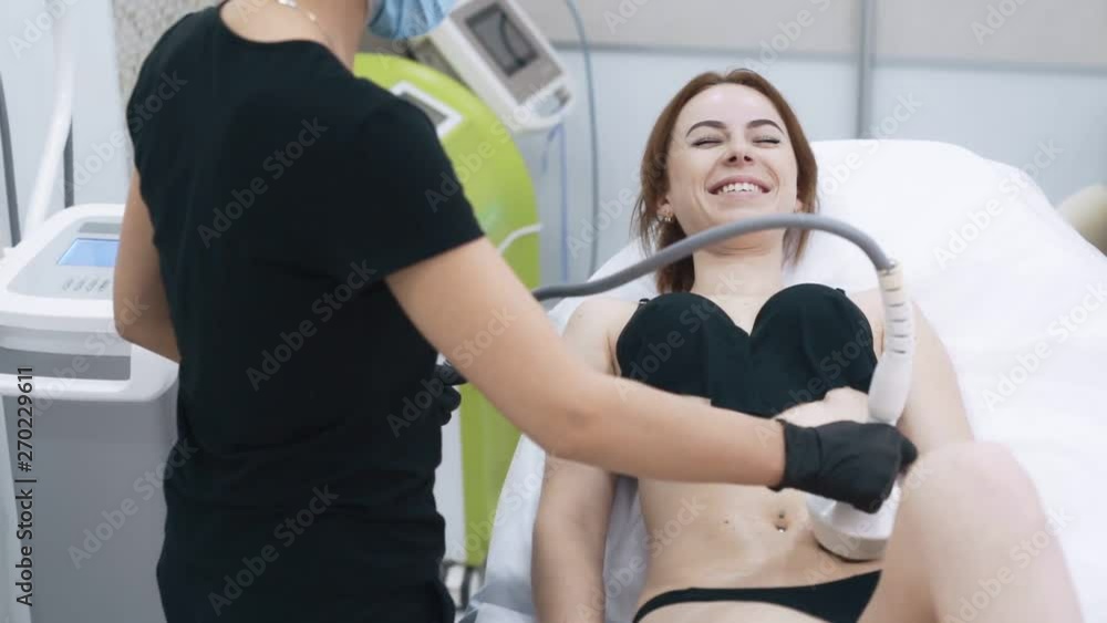 Young woman in office of cosmetologist does anti-cellulite therapy, slow motion Young woman in office of cosmetologist does anti-cellulite therapy, slow motion