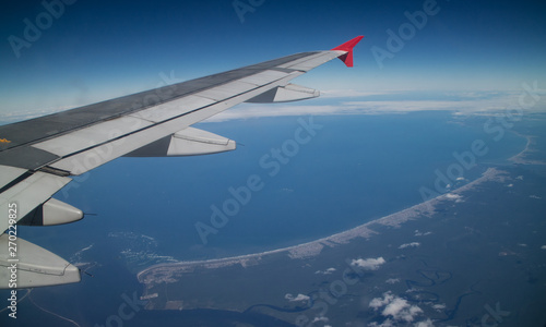 Vista do litoral brasileiro visto do alto com destaque para asa do avião, indicando que estamos abordo da aeronave