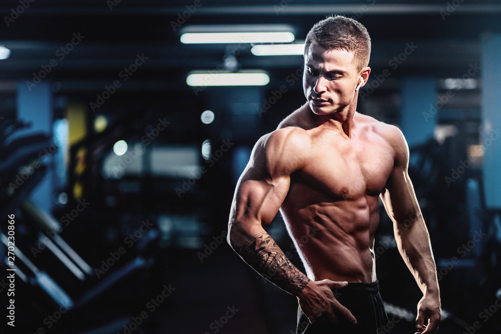 Side view of a caucasian handsome fitness model posing in the gym. Man ...