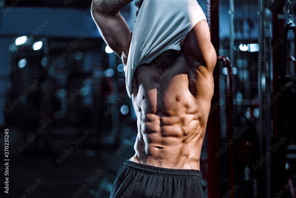 Side view of a caucasian handsome fitness model posing in the gym. Man on  diet flexing muscles and six pack abs Stock Photo