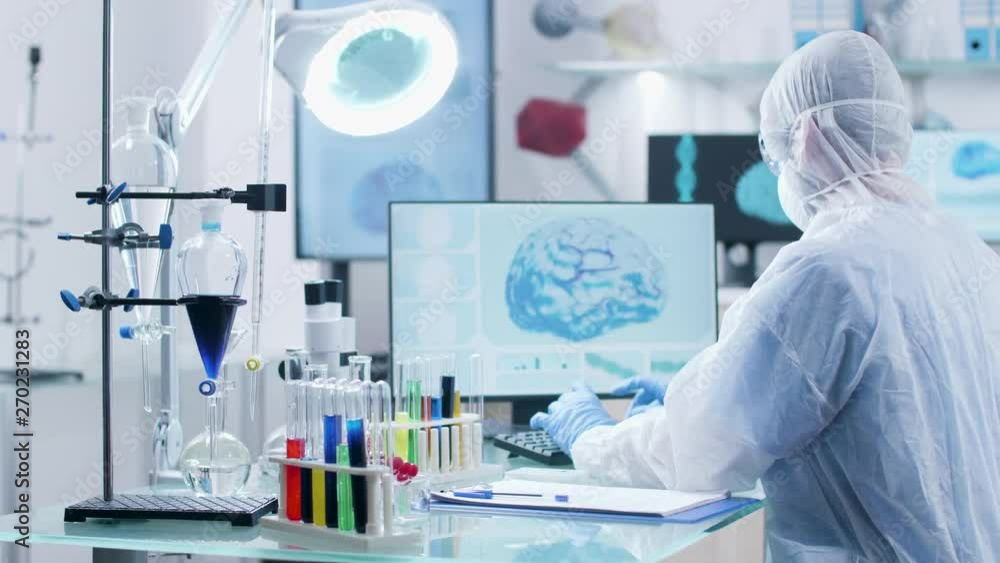 Dolly shot of chemist researcher working in high end laboratory. Different colored samples are in tubes on the desk and 3D brain scan is displayed on the monitor Dolly shot of chemist researcher working in high end laboratory. Different colored samples are in tubes on the desk and 3D brain scan is displayed on the monitor