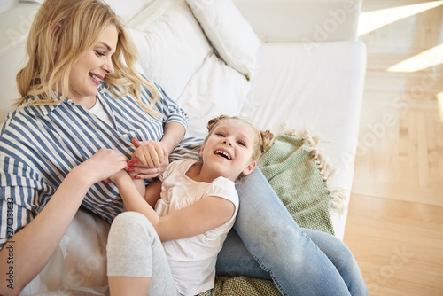 Joyful loving mother spending time with her cute daughter at home