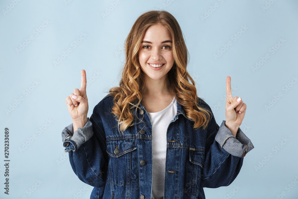 Young excited pretty woman posing isolated over blue wall background pointing. Young excited pretty woman posing isolated over blue wall background pointing.