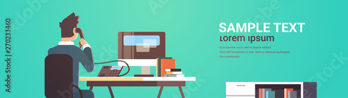 businessman sitting at workplace desk rear view business man using computer while talking on landline phone working process concept flat portrait horizontal copy space