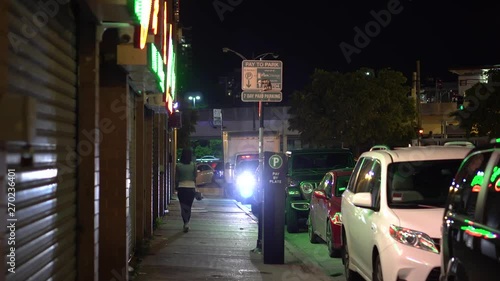 Young woman walking alone at night around Chinatown square. the car light illuminate her path down the quite city street.