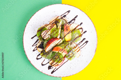 Tasty fruit salad on bright pastel background