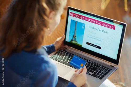woman with online travel site on laptop holding blue credit card