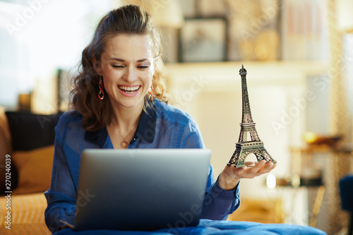 happy modern woman with souvenir of eiffel tower using laptop