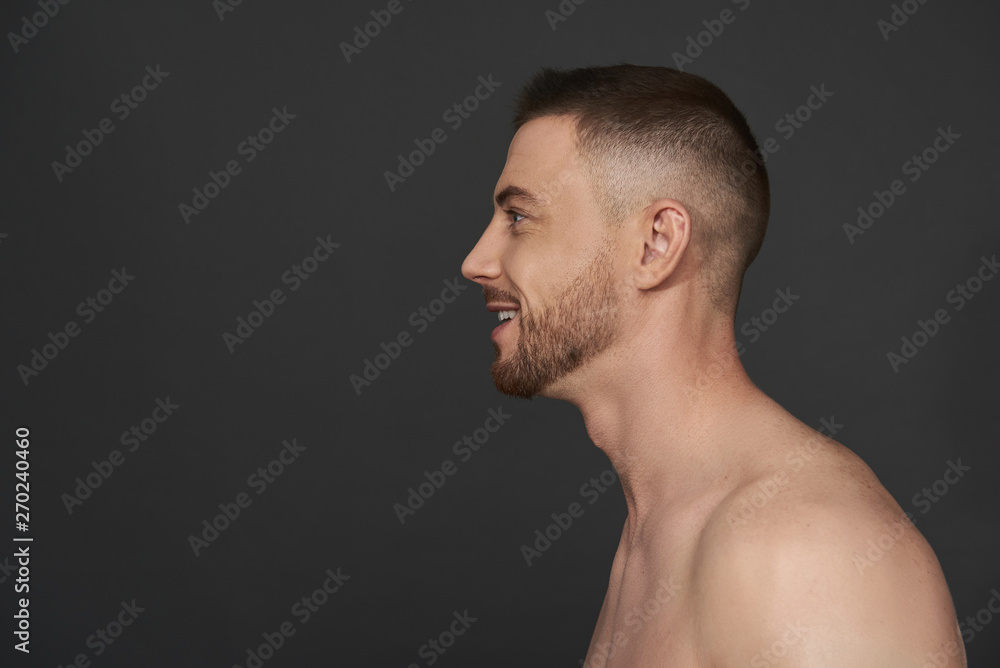 Profile of handsome bearded young man standing against gray background Profile of handsome bearded young man standing against gray background