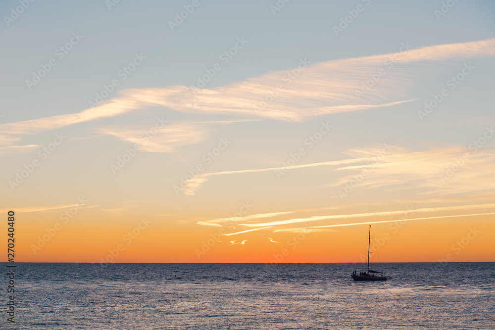 Lonely boat floats on a quiet warm calm sea against the backdrop of a golden sunset on a warm summer evening. Advertising space
