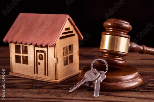 wooden house, judge hammer, keys on wooden background. legal right to real estate. photo