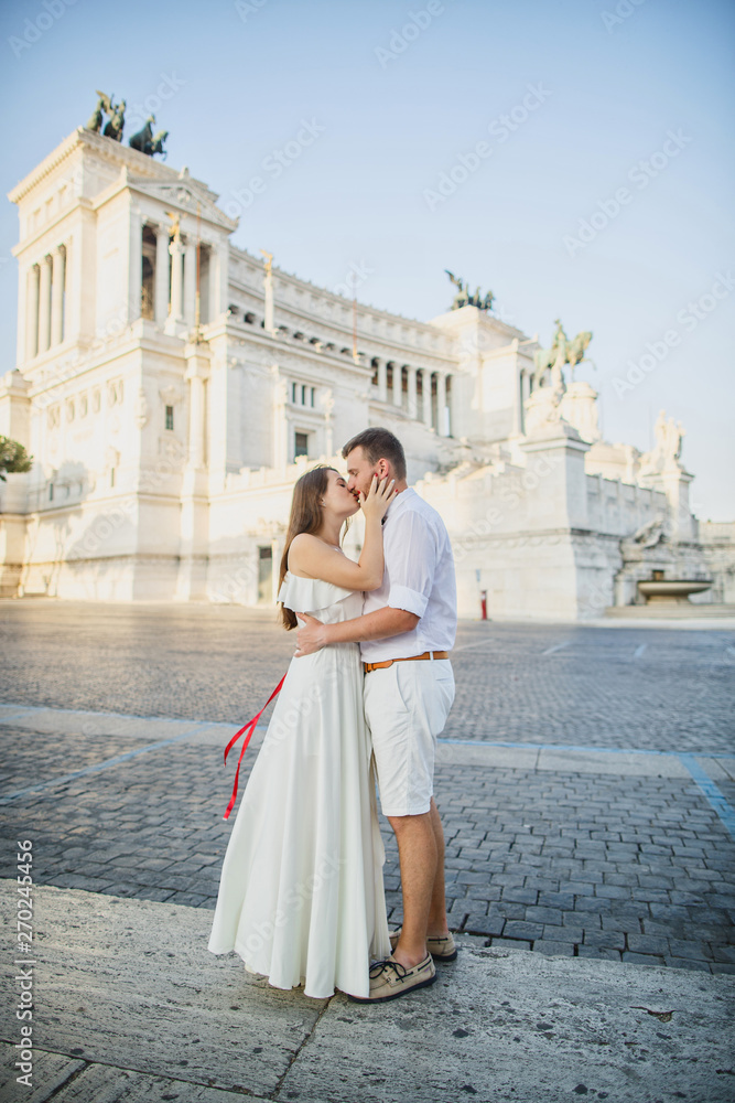 young beautiful couple in white clothes walks in Rome in Italy at sunset