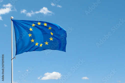 European Union flag on flag pole waving in the air on blue sky background. Copy space photo