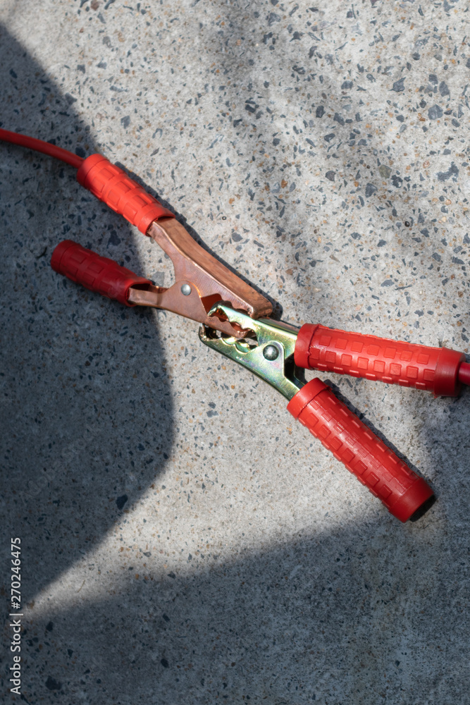 Red Jumper cables connect to another jumper cables for longer cables on cement ground. Red Jumper cables connect to another jumper cables for longer cables on cement ground.