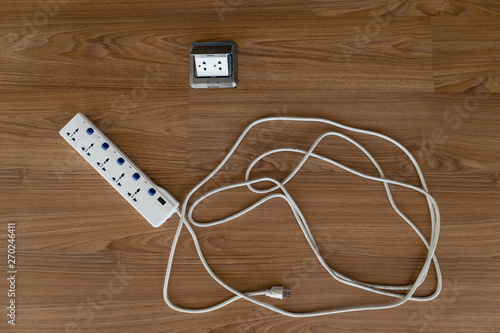 Top view of power strip after used near power outlet on the wooden floor is in a mess, Disordered concept.
