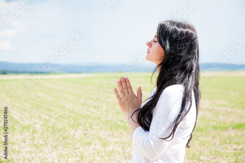 Praying hands with faith belief in God. A woman praying. Closed her eyes. Against the background of sky and clouds.