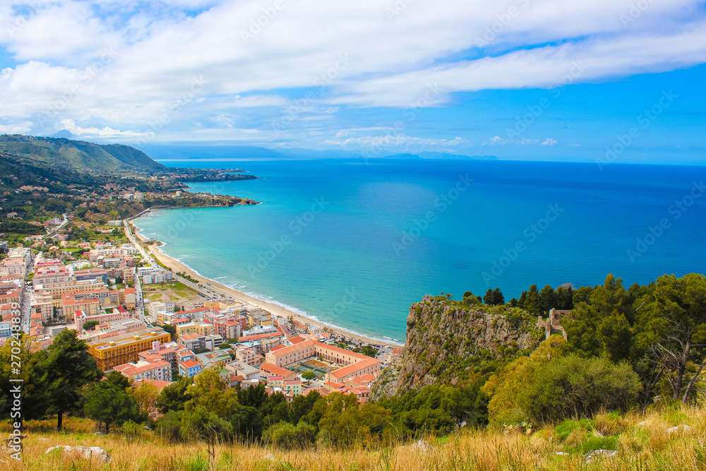 Fototapeta premium Stunning view over the bay on Tyrrhenian coast by city Cefalu, Sicily, Italy. On the adjacent rocks overlooking blue sea there are medieaval castle ruins Rocca di Cefalu. Popular tourist attraction