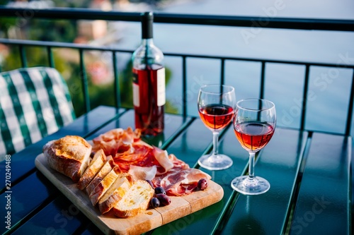 Fototapeta Naklejka Na Ścianę i Meble -  Two glasses of wine and italian snacks  with amazing view at sunset in Italy.