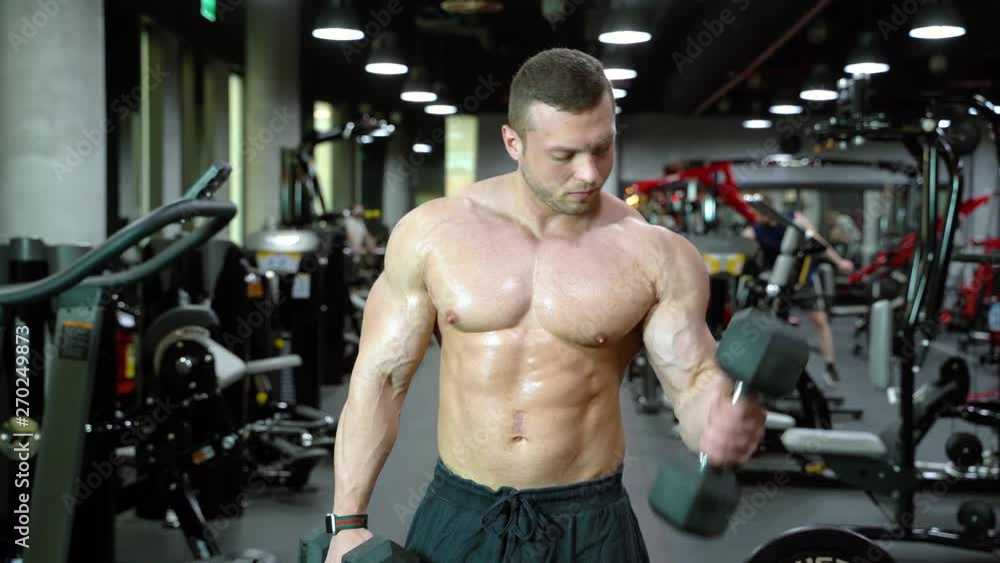 Muscular bodybuilder handsome man with a naked torso doing exercises in gym. Muscular bodybuilder handsome man with a naked torso doing exercises in gym.